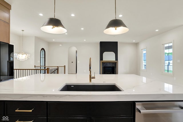 5469 Harness Dr, Greenwood, IN 46143 - kitchen featuring a sink, stainless steel dishwasher, open floor plan, dark cabinetry, and a premium fireplace