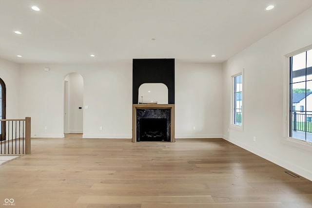 5469 Harness Dr, Greenwood, IN 46143 - unfurnished living room with arched walkways, light wood-style floors, recessed lighting, a high end fireplace, and baseboards