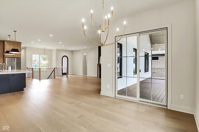 5469 Harness Dr, Greenwood, IN 46143 - unfurnished dining area with a chandelier, arched walkways, light wood-style floors, recessed lighting, and baseboards