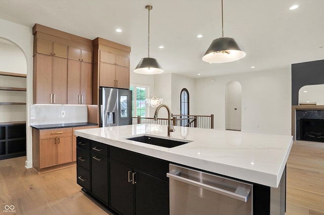 5469 Harness Dr, Greenwood, IN 46143 - kitchen with stainless steel appliances, a sink, light wood-style floors, arched walkways, and an island with sink
