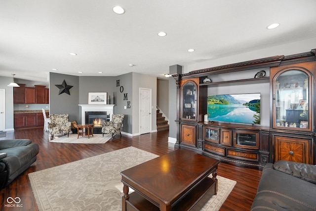 living room with a tile fireplace and dark wood-type flooring