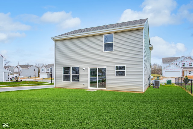 rear view of house with a lawn and central AC