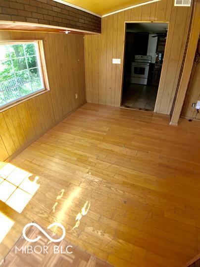 empty room with light wood-type flooring and wooden walls