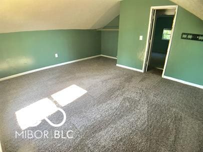 additional living space with vaulted ceiling and dark colored carpet