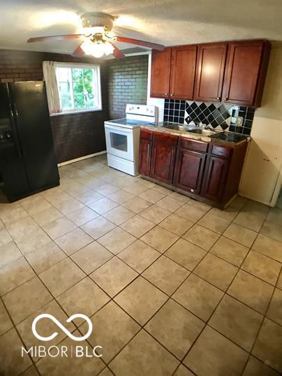 kitchen featuring black fridge, tile countertops, white range with electric stovetop, ceiling fan, and backsplash