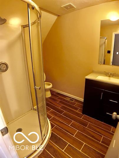 bathroom with vanity, a shower with shower door, and toilet