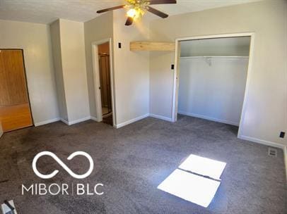 unfurnished bedroom with ceiling fan, a closet, and dark colored carpet