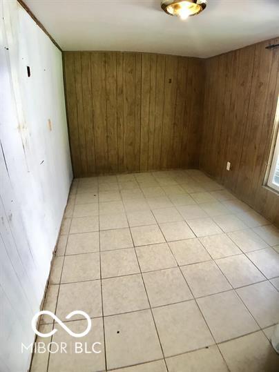 tiled spare room featuring wooden walls