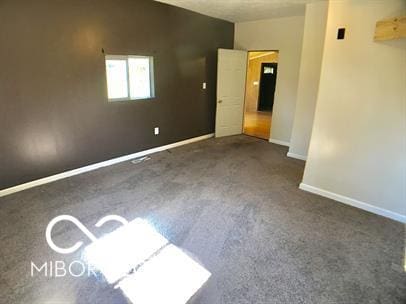 spare room with dark colored carpet