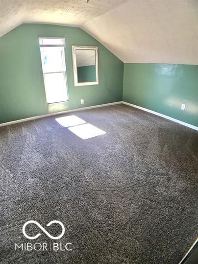 bonus room with vaulted ceiling and carpet flooring