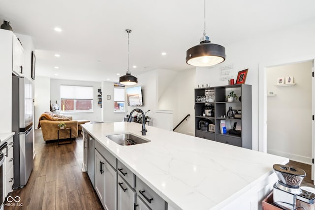 kitchen featuring sink, dark hardwood / wood-style floors, light stone countertops, decorative light fixtures, and stainless steel appliances