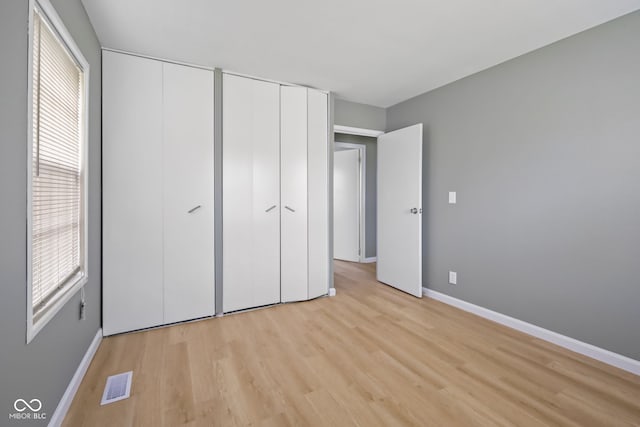 unfurnished bedroom with multiple closets and light hardwood / wood-style floors