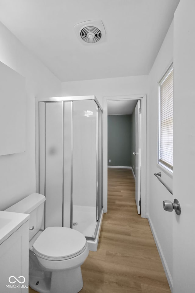 bathroom with hardwood / wood-style floors, vanity, toilet, and a shower with shower door