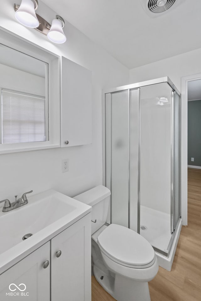 bathroom featuring walk in shower, vanity, hardwood / wood-style flooring, and toilet