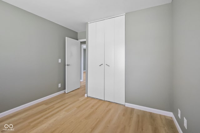 unfurnished bedroom with light wood-type flooring and a closet