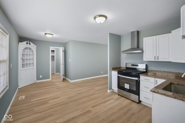 kitchen featuring light hardwood / wood-style floors, white cabinetry, sink, wall chimney exhaust hood, and stainless steel range oven