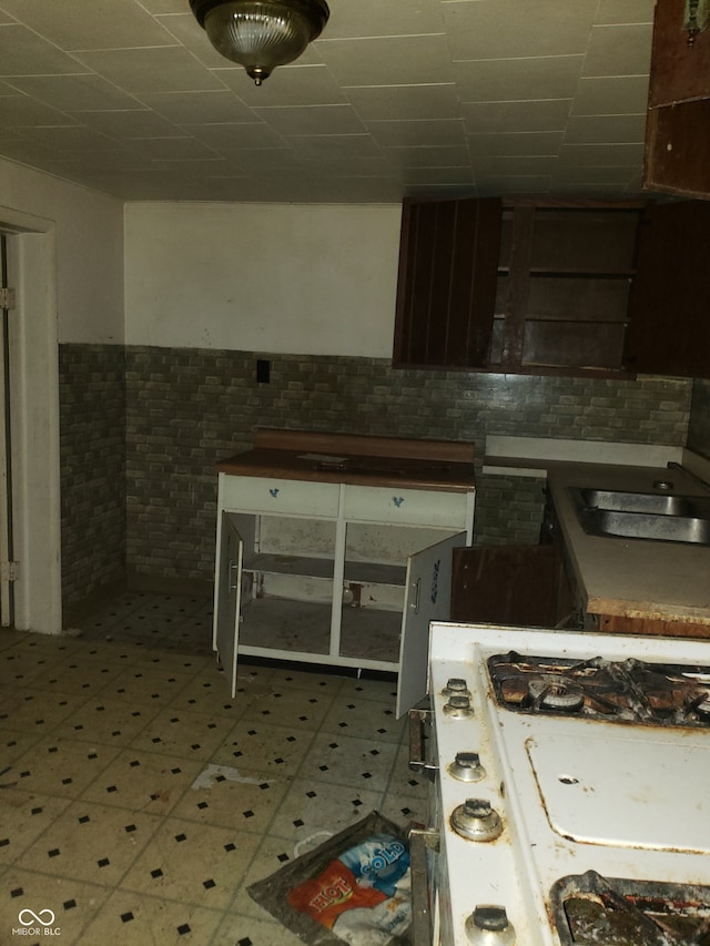 kitchen featuring white gas stove and tile walls