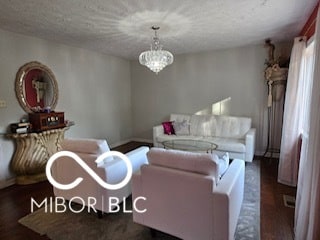 living room with dark hardwood / wood-style flooring, a textured ceiling, and a chandelier