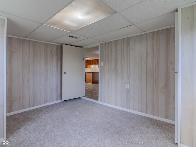 interior space featuring a drop ceiling and wooden walls