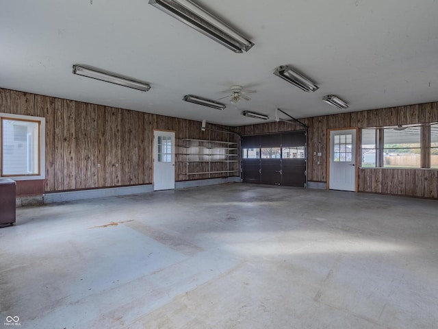 garage featuring ceiling fan and wooden walls