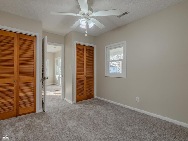 unfurnished bedroom with ceiling fan, a textured ceiling, and light carpet