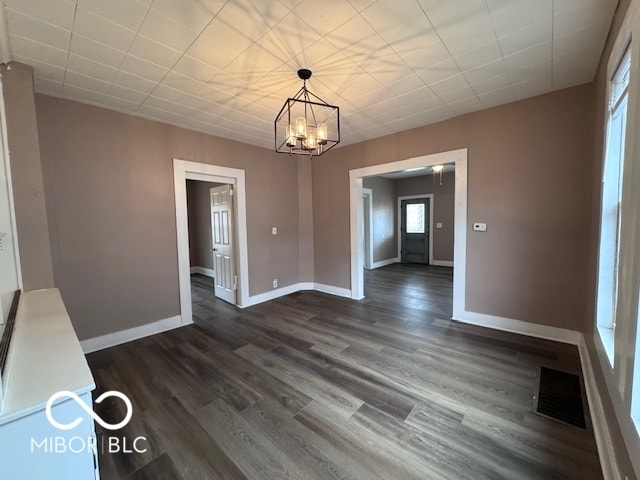 unfurnished dining area featuring dark wood-type flooring and a notable chandelier