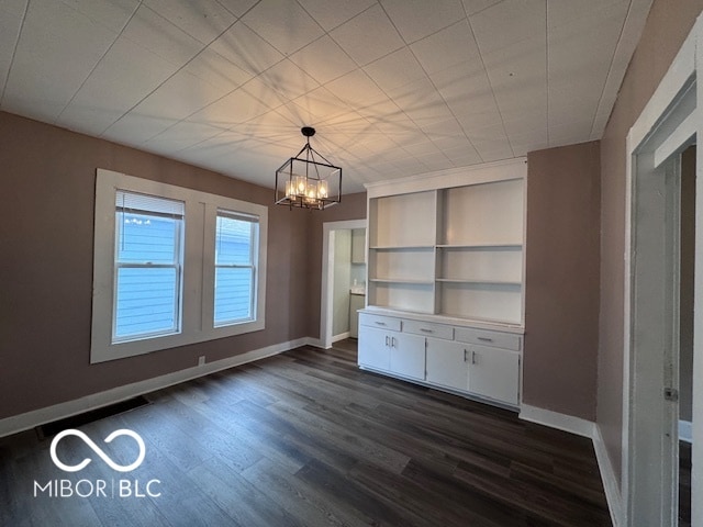 unfurnished dining area with dark hardwood / wood-style flooring, built in features, and a chandelier