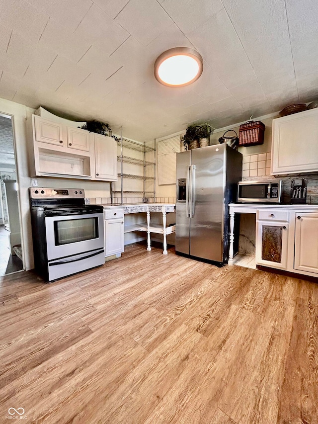 kitchen with light hardwood / wood-style flooring, white cabinetry, decorative backsplash, and stainless steel appliances