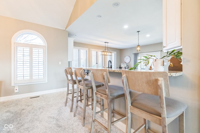 kitchen with a breakfast bar area, kitchen peninsula, light carpet, and light stone counters