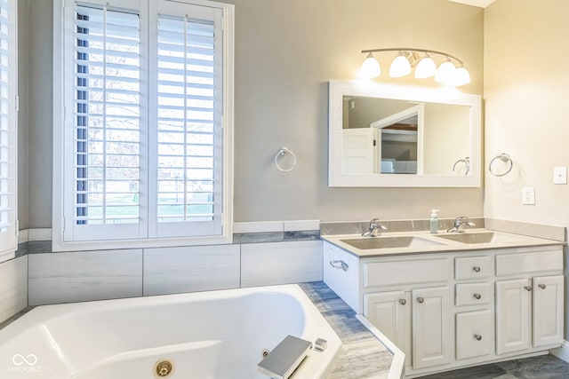 bathroom featuring vanity, a relaxing tiled tub, and a healthy amount of sunlight