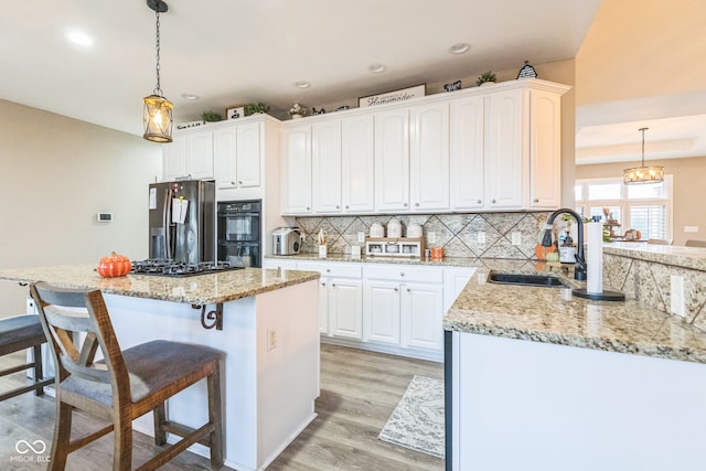 kitchen with black appliances, white cabinets, and hanging light fixtures