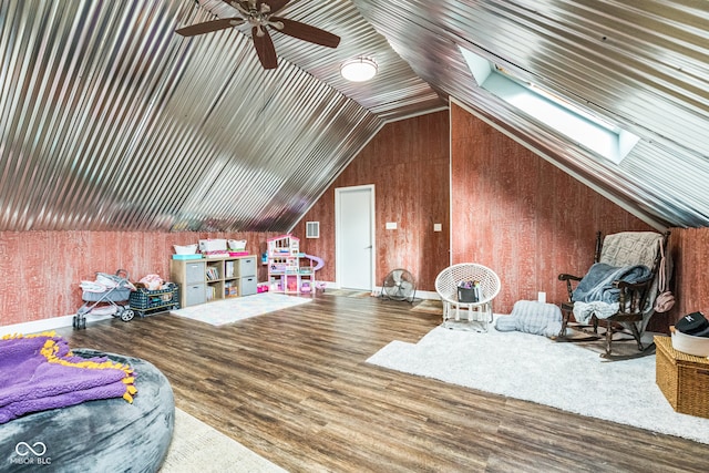 interior space with lofted ceiling with skylight, wood walls, and hardwood / wood-style flooring