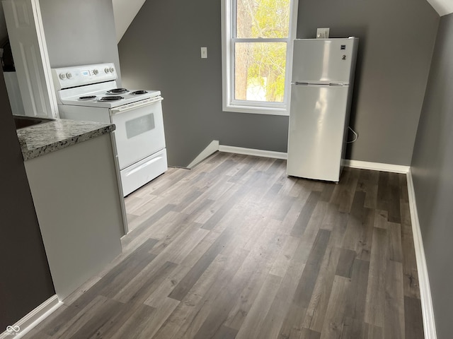 kitchen with light stone countertops, wood-type flooring, white appliances, and vaulted ceiling