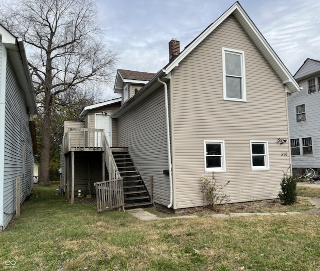 back of property featuring a wooden deck and a yard