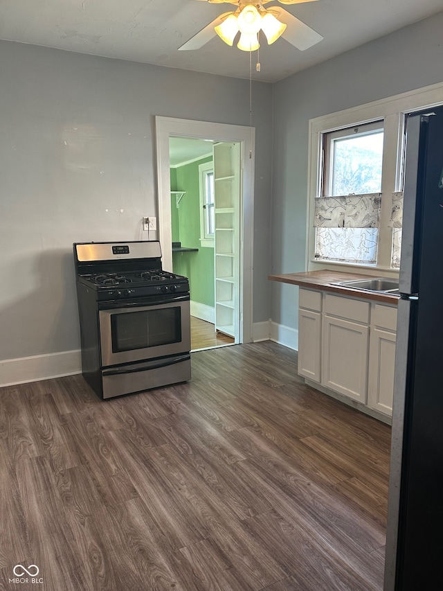 kitchen featuring white cabinets, stainless steel range with gas stovetop, dark hardwood / wood-style floors, ceiling fan, and fridge