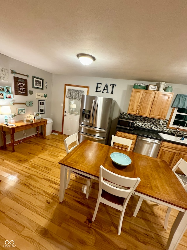 kitchen featuring sink, light wood-type flooring, appliances with stainless steel finishes, and tasteful backsplash