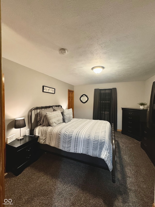 bedroom featuring dark colored carpet and a textured ceiling