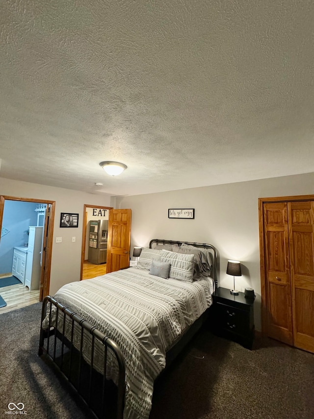 bedroom featuring carpet, a textured ceiling, and ensuite bath