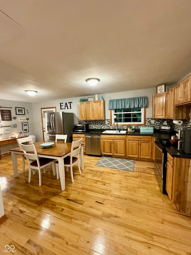 kitchen featuring stainless steel appliances, sink, light wood-type flooring, and tasteful backsplash