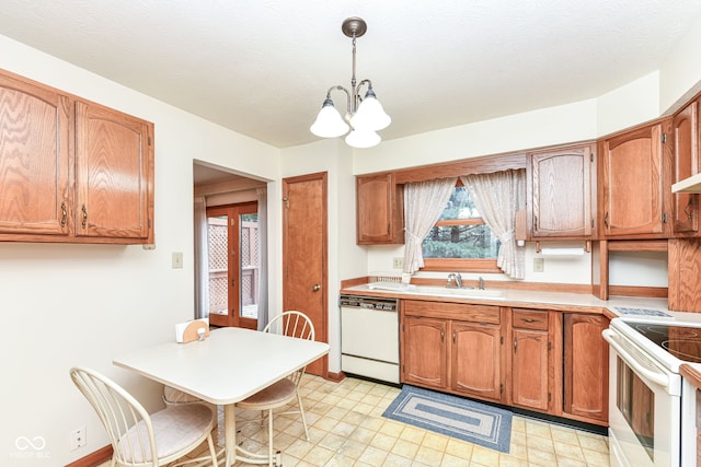 kitchen featuring white appliances, sink, decorative light fixtures, a textured ceiling, and a notable chandelier