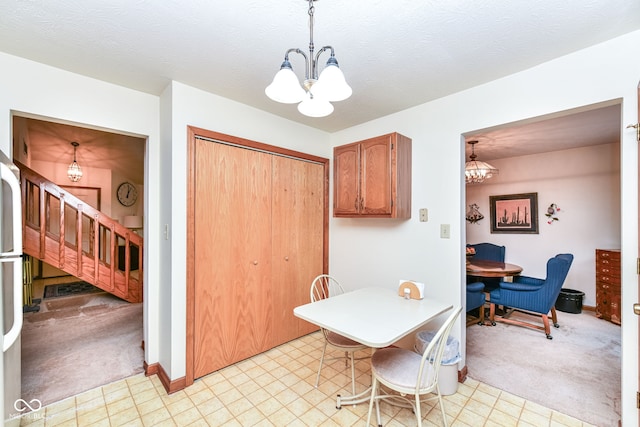 kitchen featuring light carpet, pendant lighting, a textured ceiling, and a notable chandelier