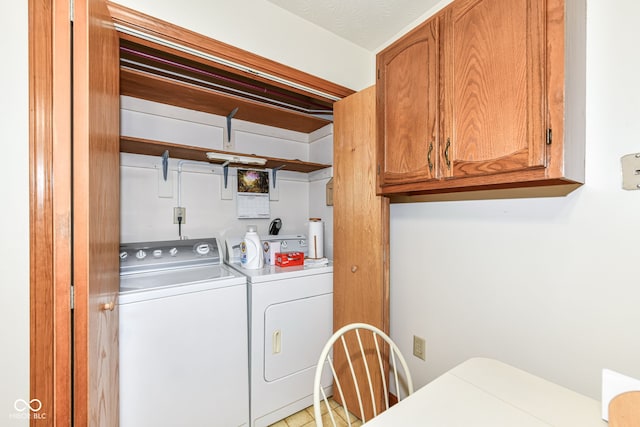 clothes washing area with cabinets, a textured ceiling, and washer and clothes dryer