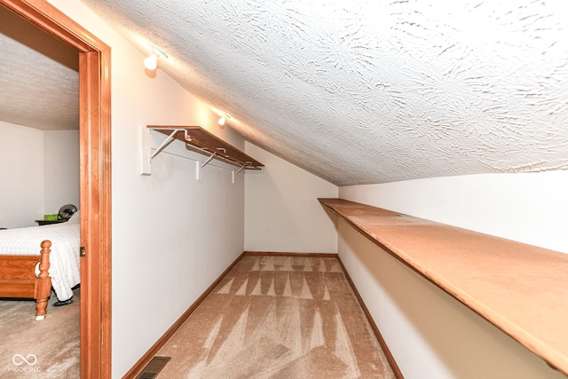 spacious closet with light colored carpet and lofted ceiling