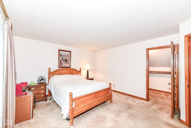 bedroom featuring light colored carpet, a walk in closet, and a closet