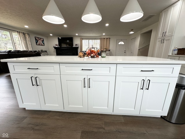 kitchen with dark hardwood / wood-style floors, white cabinetry, decorative light fixtures, and a textured ceiling