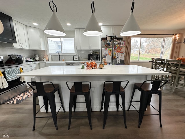 kitchen featuring white cabinetry, decorative light fixtures, appliances with stainless steel finishes, and a center island