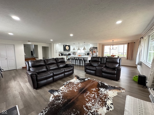 living room with hardwood / wood-style flooring, a chandelier, and a textured ceiling