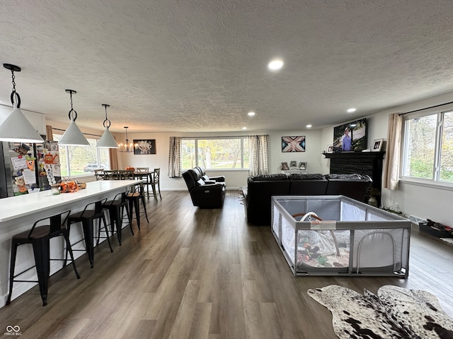 interior space with a kitchen bar, a textured ceiling, stainless steel fridge, pendant lighting, and dark hardwood / wood-style flooring