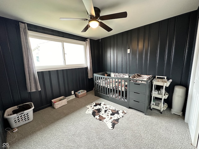 bedroom with a nursery area, carpet, and ceiling fan