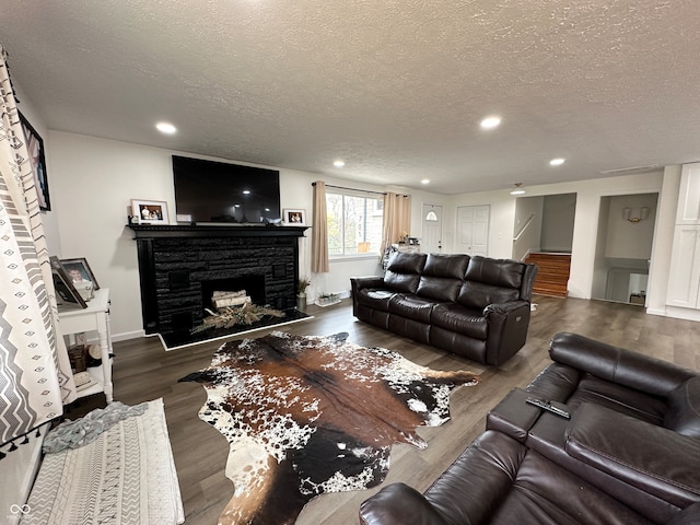 living room featuring a fireplace, dark hardwood / wood-style flooring, and a textured ceiling